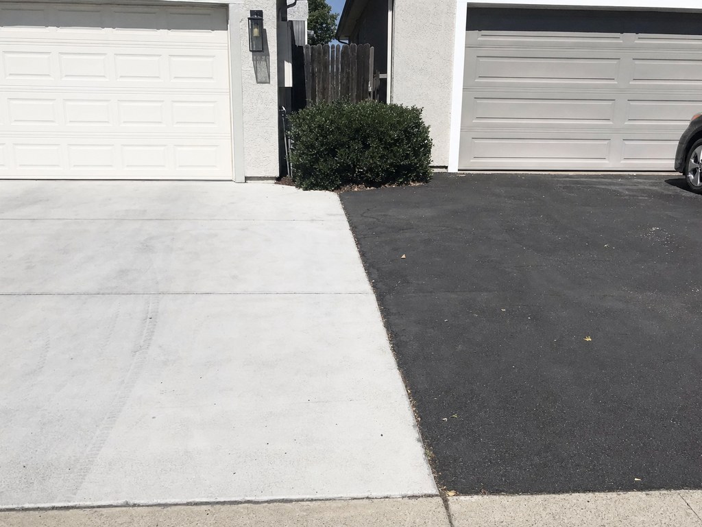 A concrete driveway next to an asphalt driveway in front of two Stockton homes